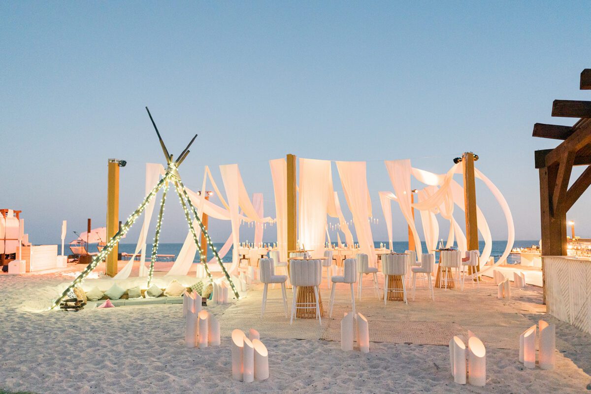 Los Cabos destination wedding setup on the beach with draped fabric and lighting.