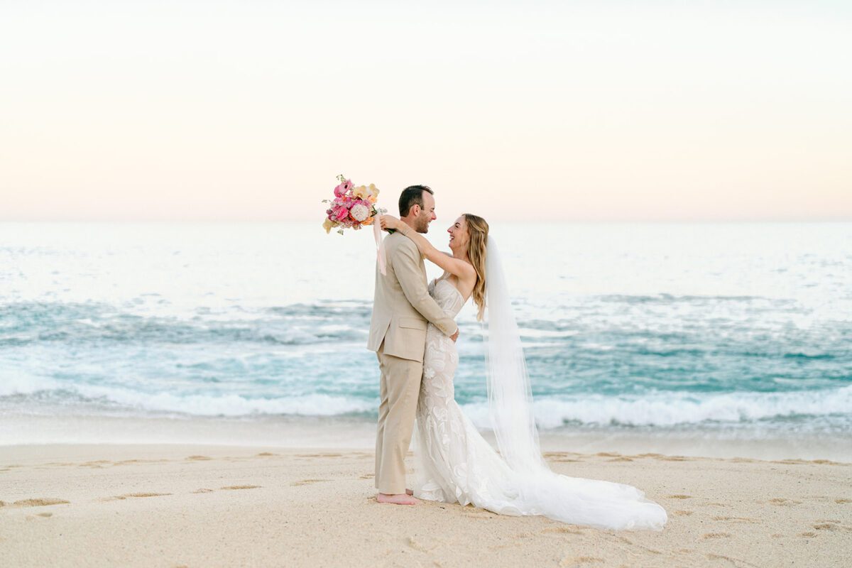 Los Cabos destination wedding: Bride and groom embrace on the beach at Hilton Los Cabos.