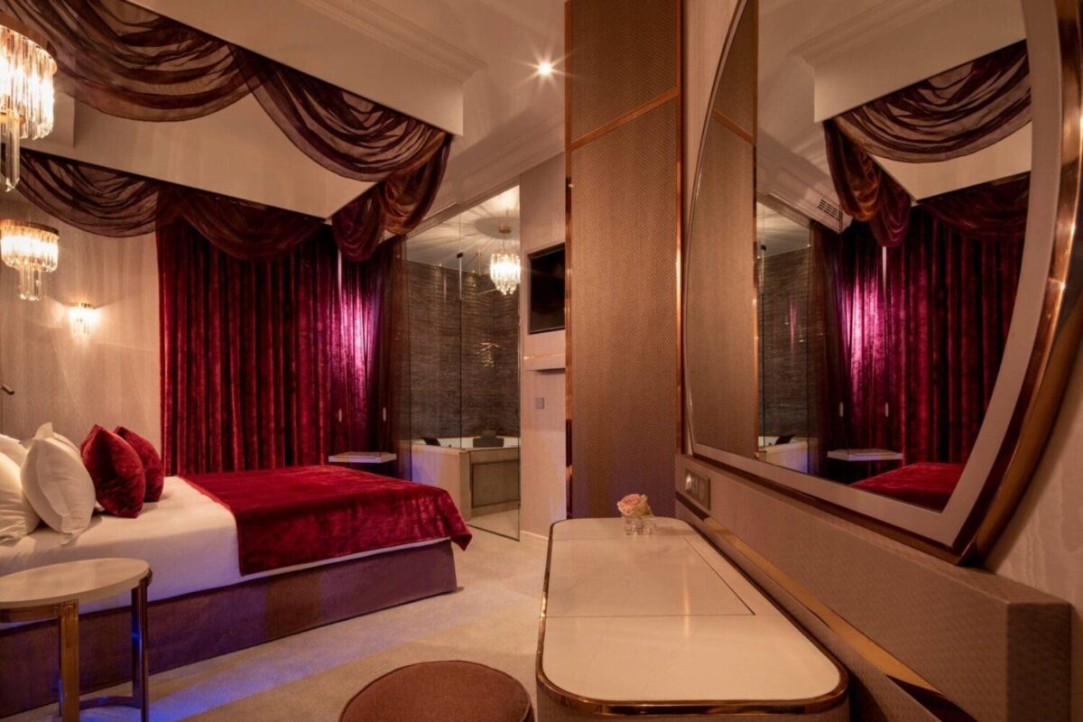 Luxurious Paris hotel suite with a king-size bed and a large mirror. Perfect for a romantic honeymoon getaway.