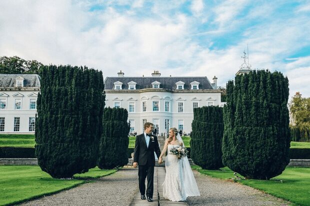 Bride and groom walking at elegant estate, showcasing Irish wedding traditions
