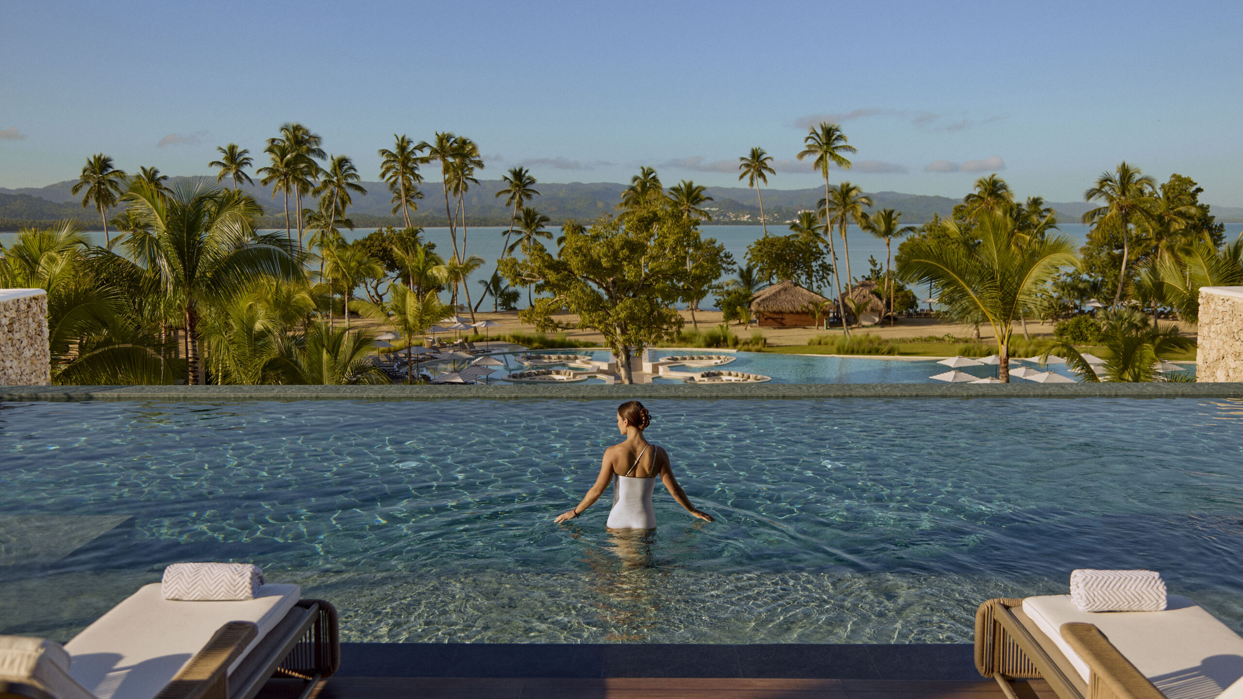 Woman at Zemi Miches All-Inclusive Resort infinity pool, ocean view.