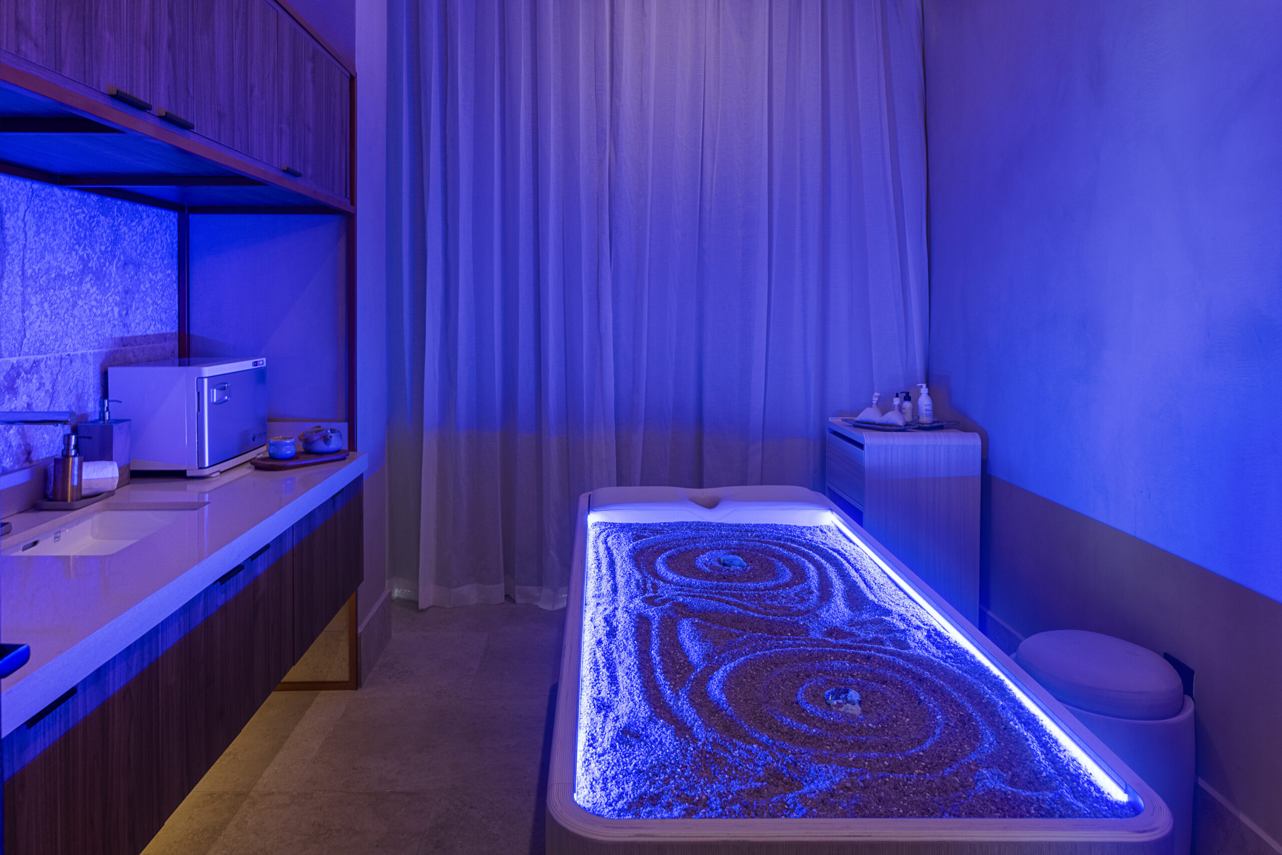 Zemi Miches spa treatment room with sand bed and blue lighting