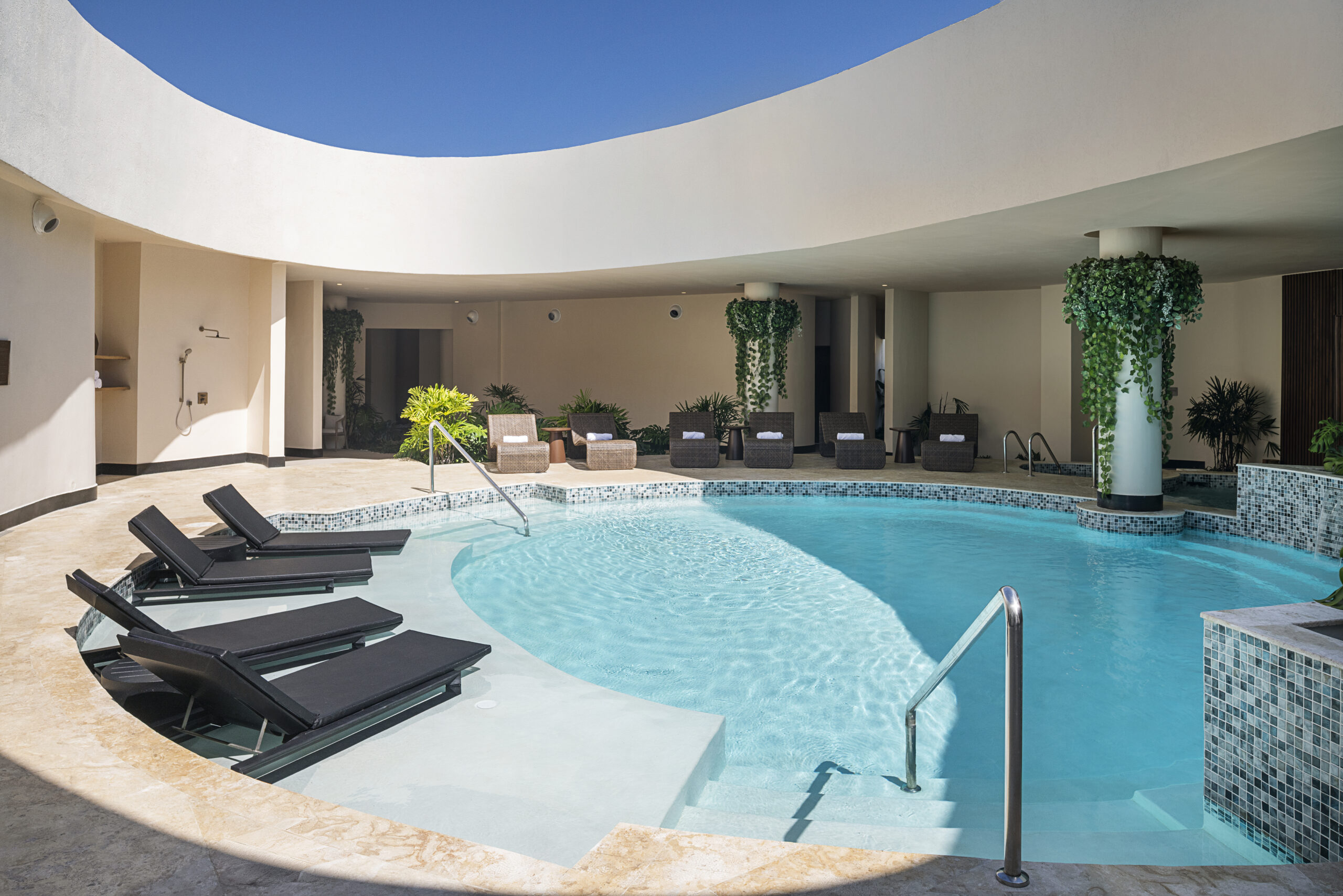 Zemi Miches resort pool area with lounge chairs and clear blue water.
