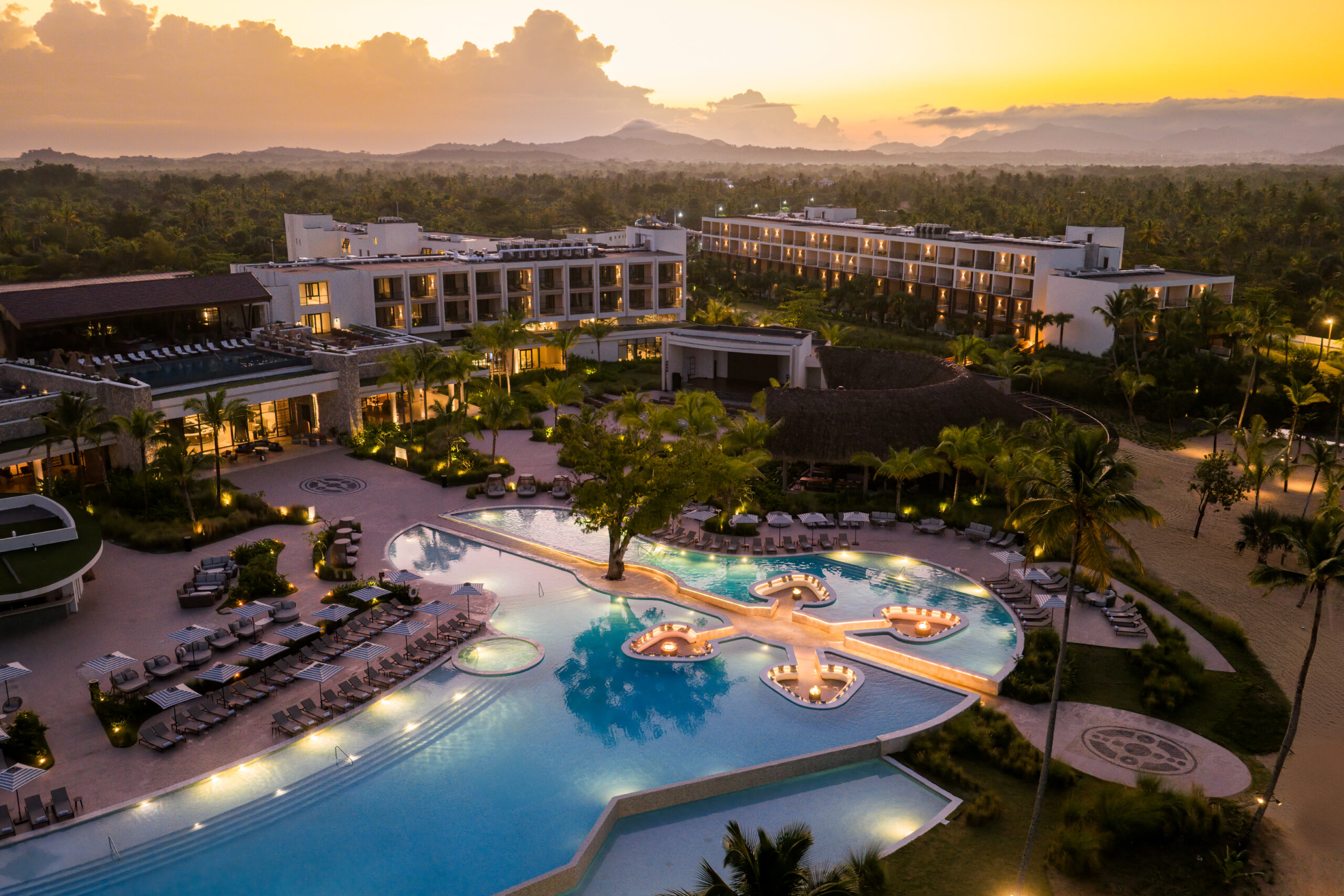 Zemi Miches All-Inclusive Resort at sunset, featuring a large pool and palm trees.