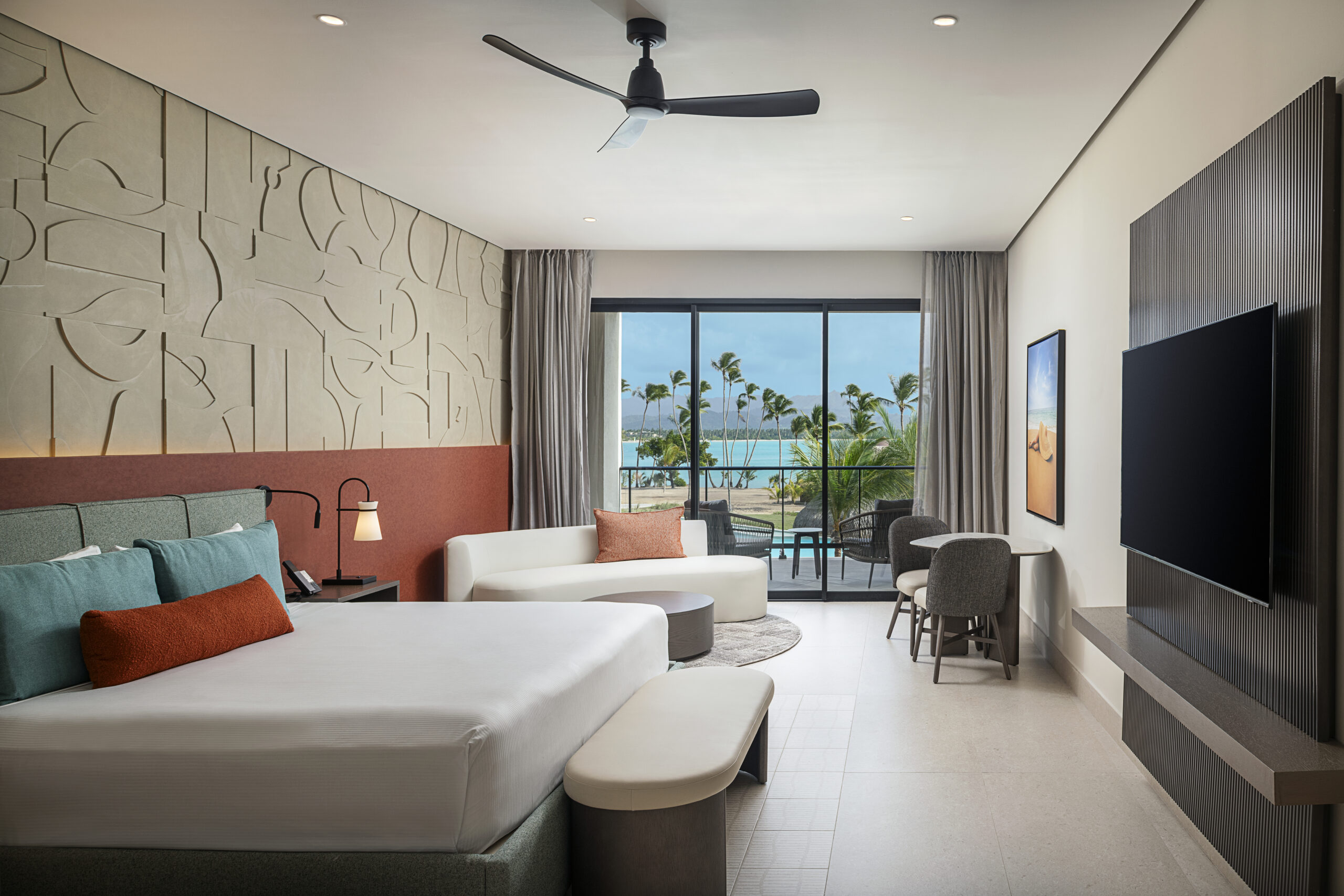 Zemi Miches All-Inclusive Resort bedroom with large bed, couch, balcony, ocean view