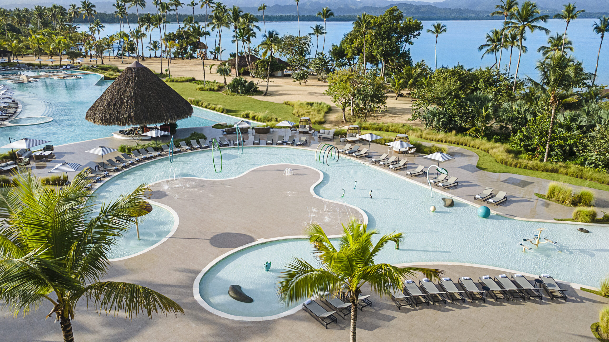 Aerial view of Zemi Miches All-Inclusive Resort's expansive pool area with palm trees.