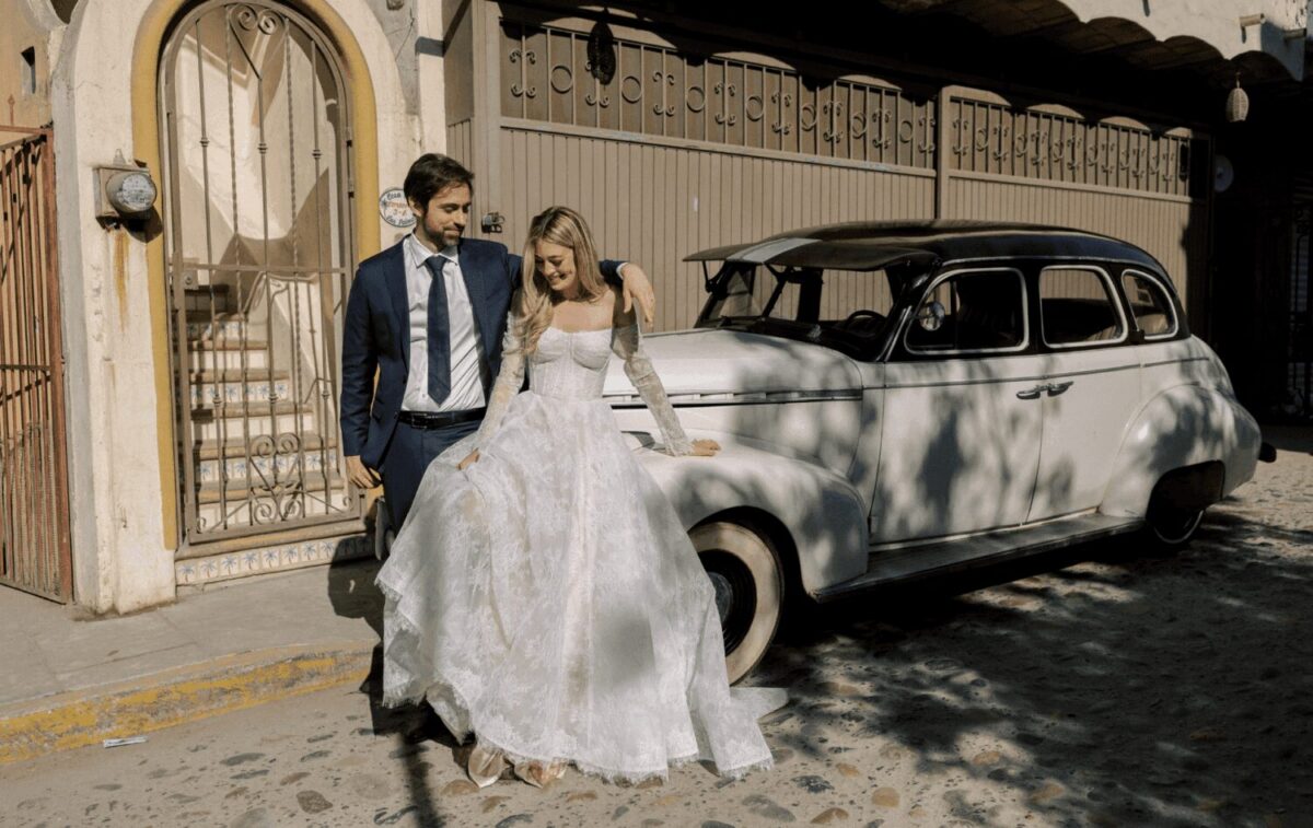 Bride and groom pose by vintage car at Auberge Resorts Collection's Susurros del Corazón.
