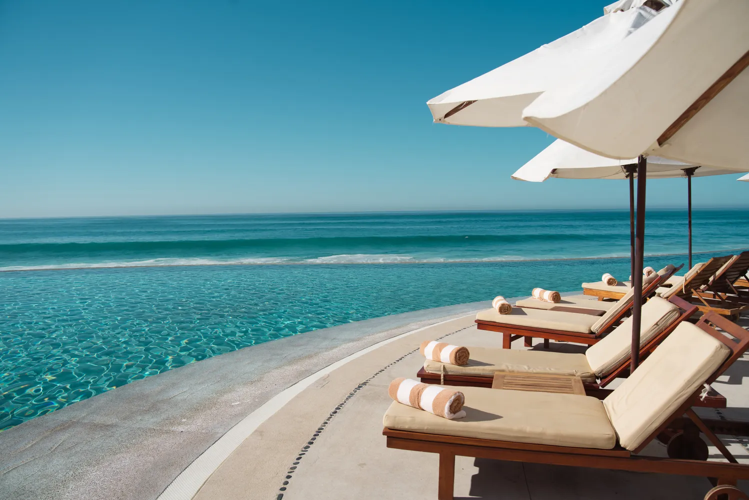 Luxury poolside lounge chairs at Marquis Los Cabos, overlooking the ocean. Perfect Los Cabos wedding destination.