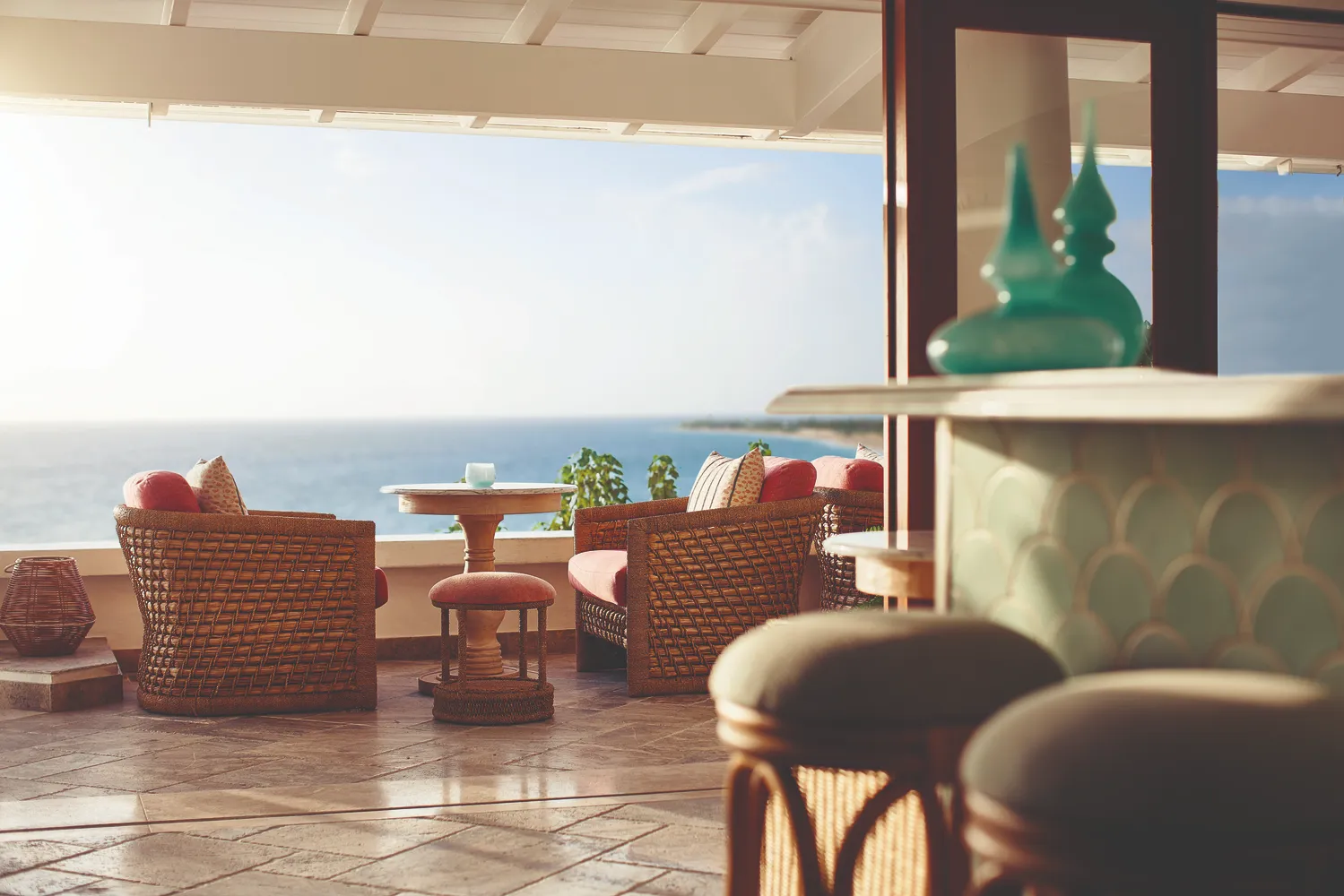 Luxury wicker chairs and table on a Caribbean resort patio overlooking the ocean. Ideal Caribbean destination wedding venue.