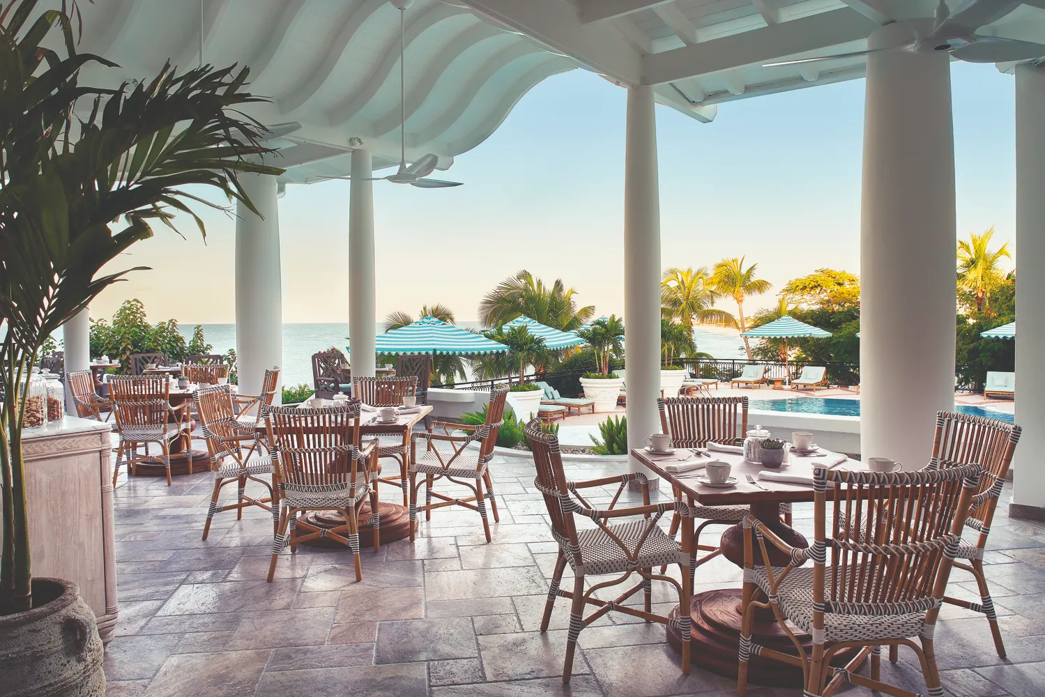 Outdoor patio dining at La Samanna, a Belmond Hotel, St. Martin. Ocean views and a pool are in the background. Perfect Caribbean destination wedding venue.