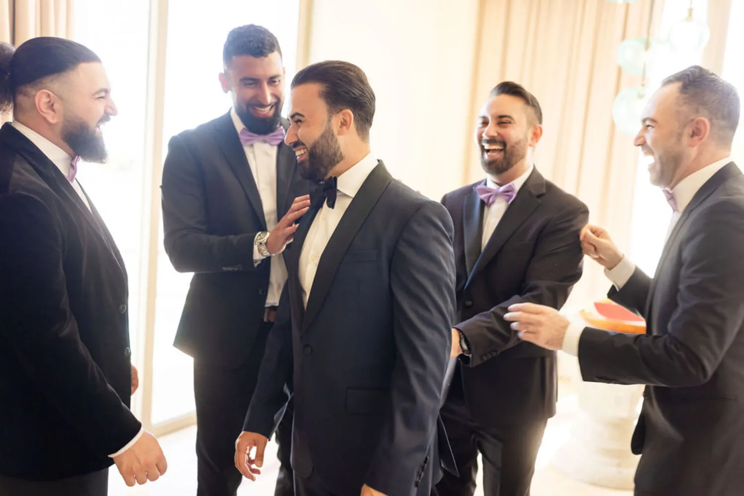 Groom and groomsmen laughing together in suits at a Los Cabos wedding.