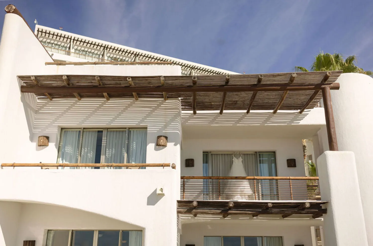 Wedding dress hangs on balcony of a white building at Marquis Los Cabos, a Los Cabos wedding destination.