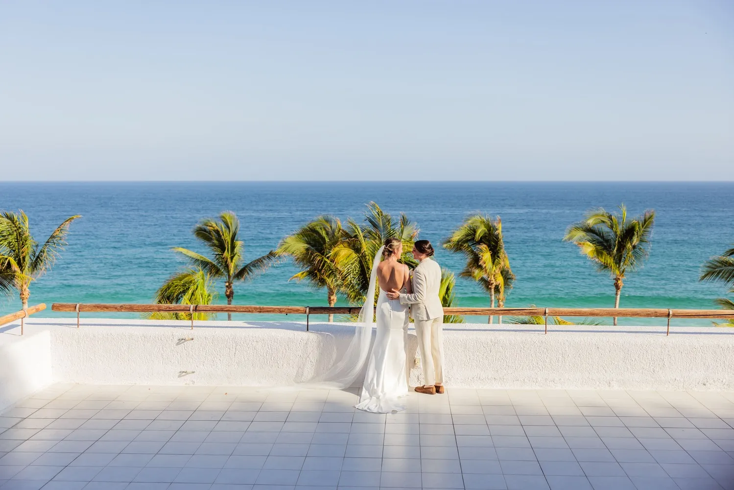 Bride and groom embrace on a Los Cabos wedding venue overlooking the ocean.