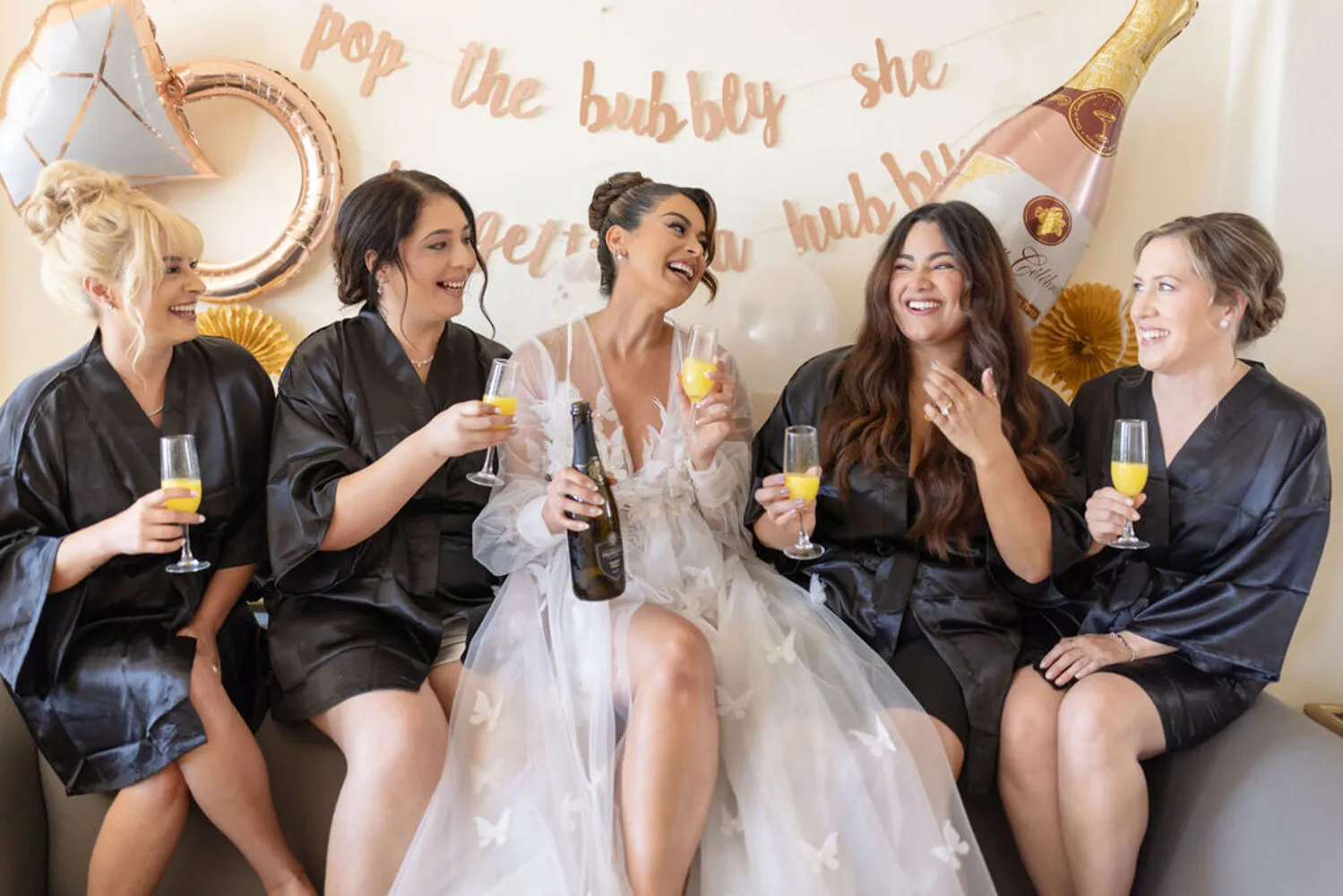 Bride and bridesmaids in black robes enjoying mimosas at a Los Cabos wedding destination.