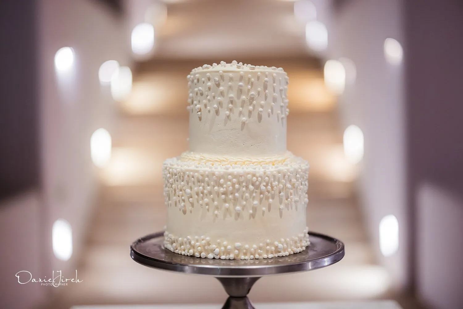 Elegant two-tiered wedding cake decorated with pearl accents.