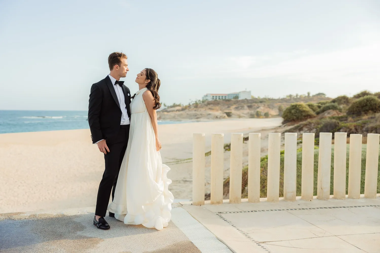 Bride and groom embrace at a Los Cabos wedding overlooking the ocean.