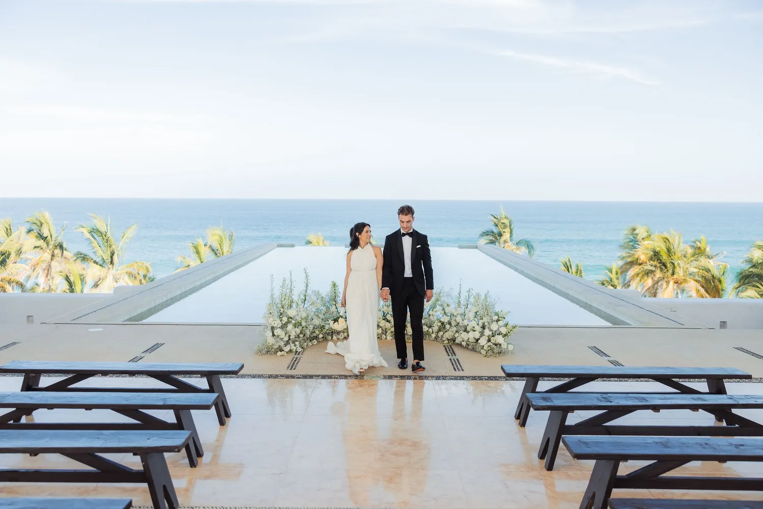 Bride and groom holding hands at a Los Cabos wedding ceremony overlooking the ocean.