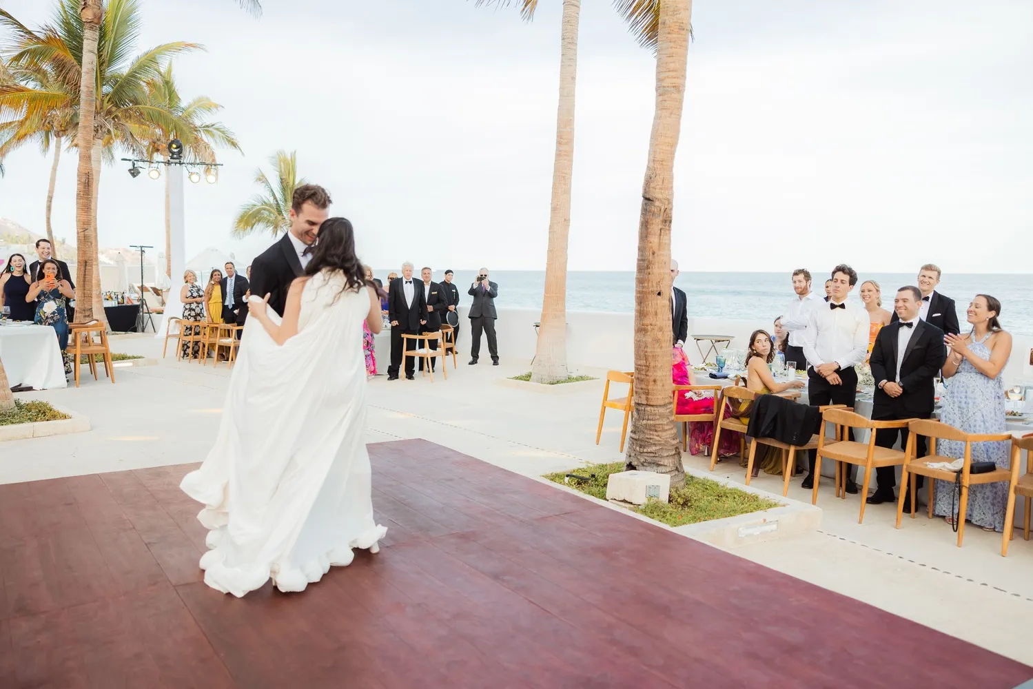 Bride and groom's first dance at a Los Cabos wedding, guests watching.