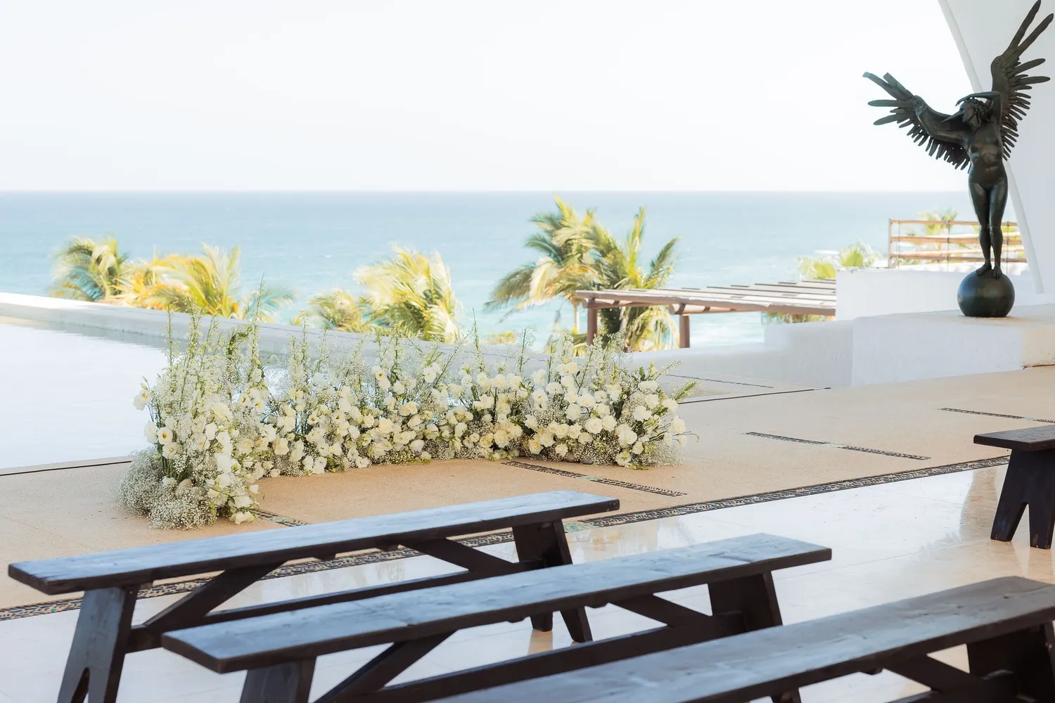 Stunning Los Cabos wedding ceremony setup with white floral arrangements and ocean view.