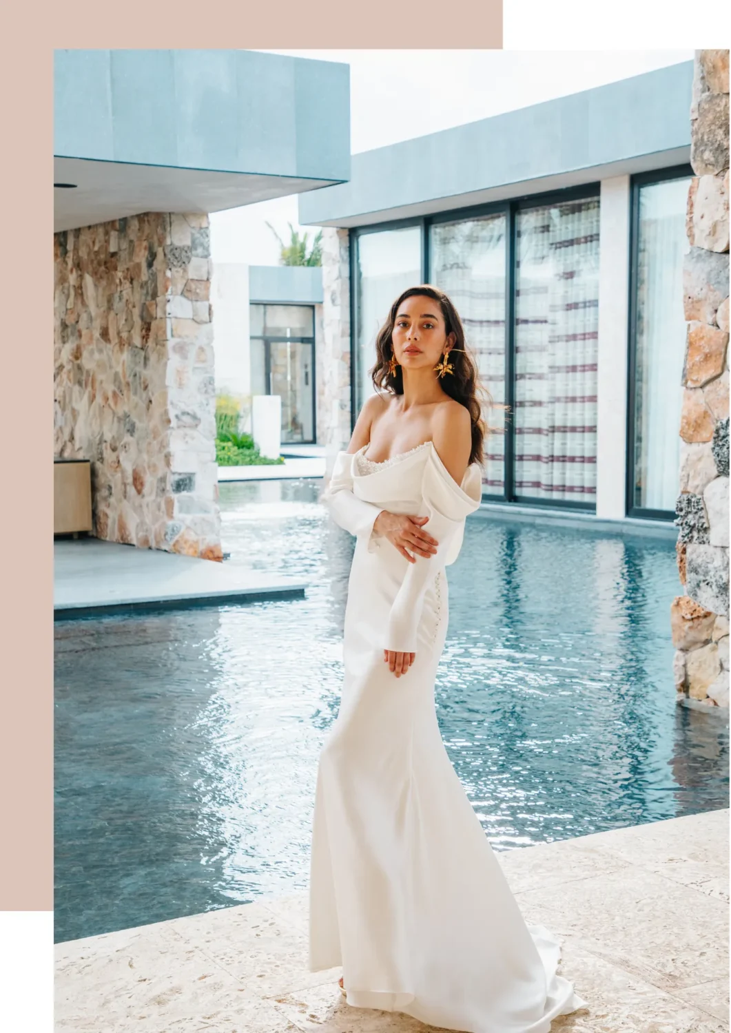 Elegant bride in off-the-shoulder white gown poses by pool