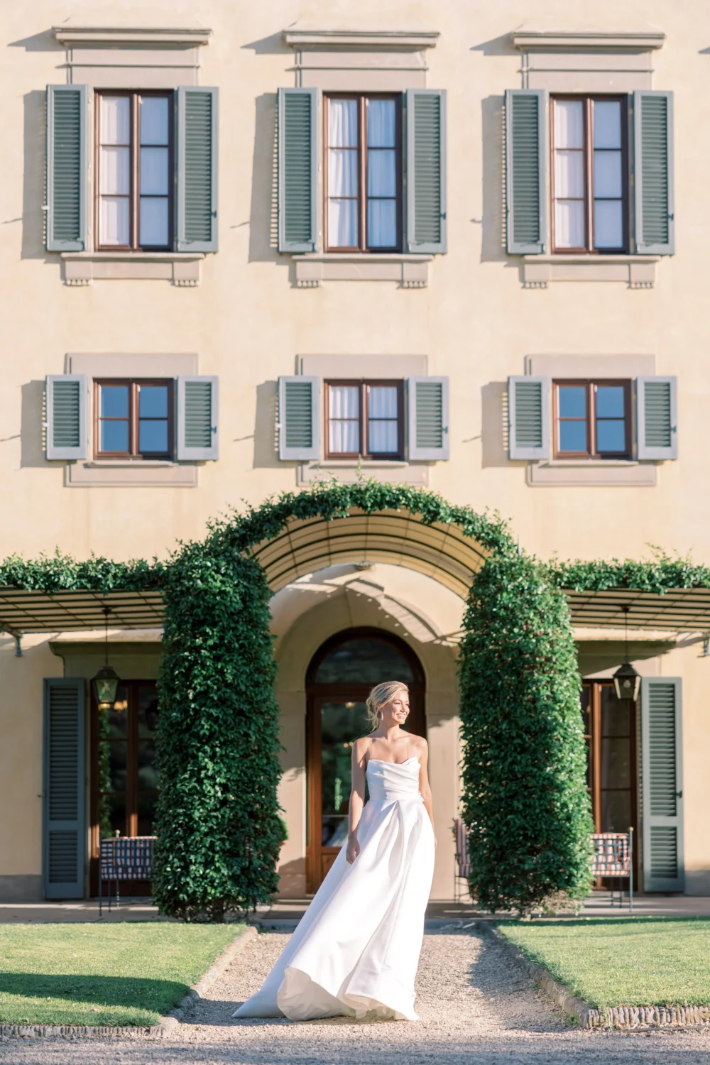 Bride in a flowing white wedding gown poses outside a beautiful Italian villa during a styled shoot.