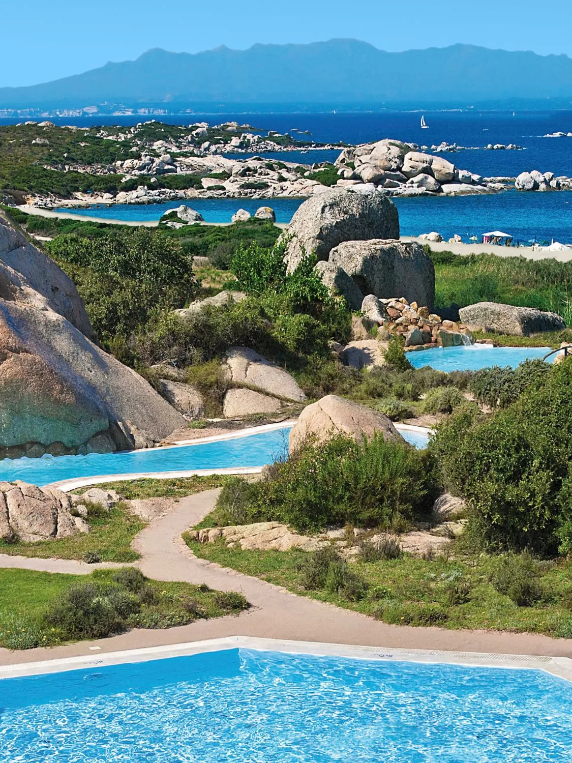 Luxury resort pools nestled among rocks overlooking a scenic ocean view.