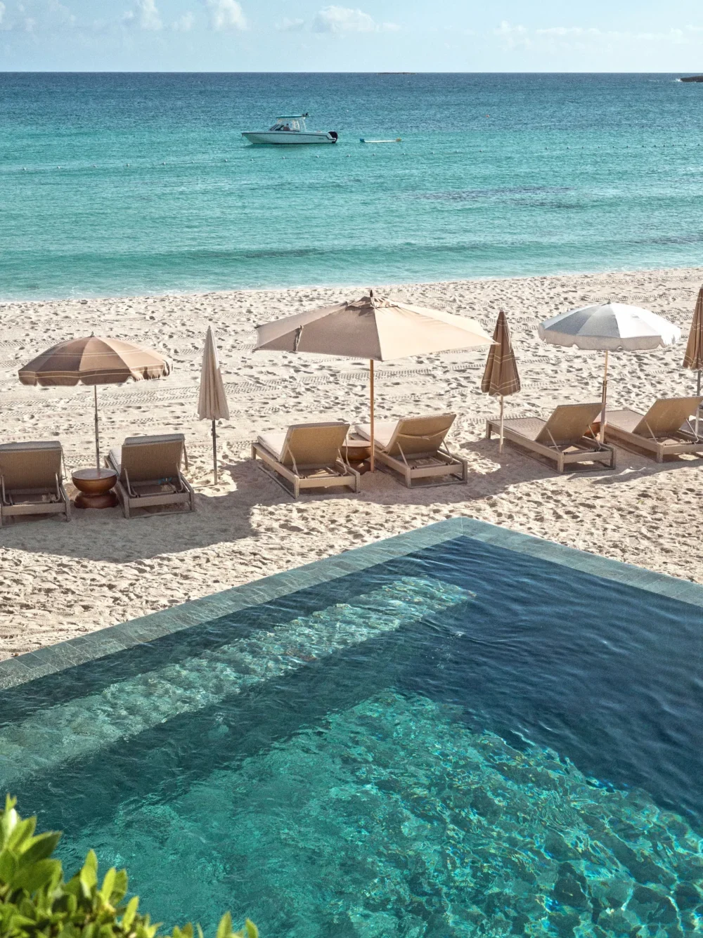 Luxury resort pool and beach with lounge chairs and umbrellas. Tranquil ocean view.