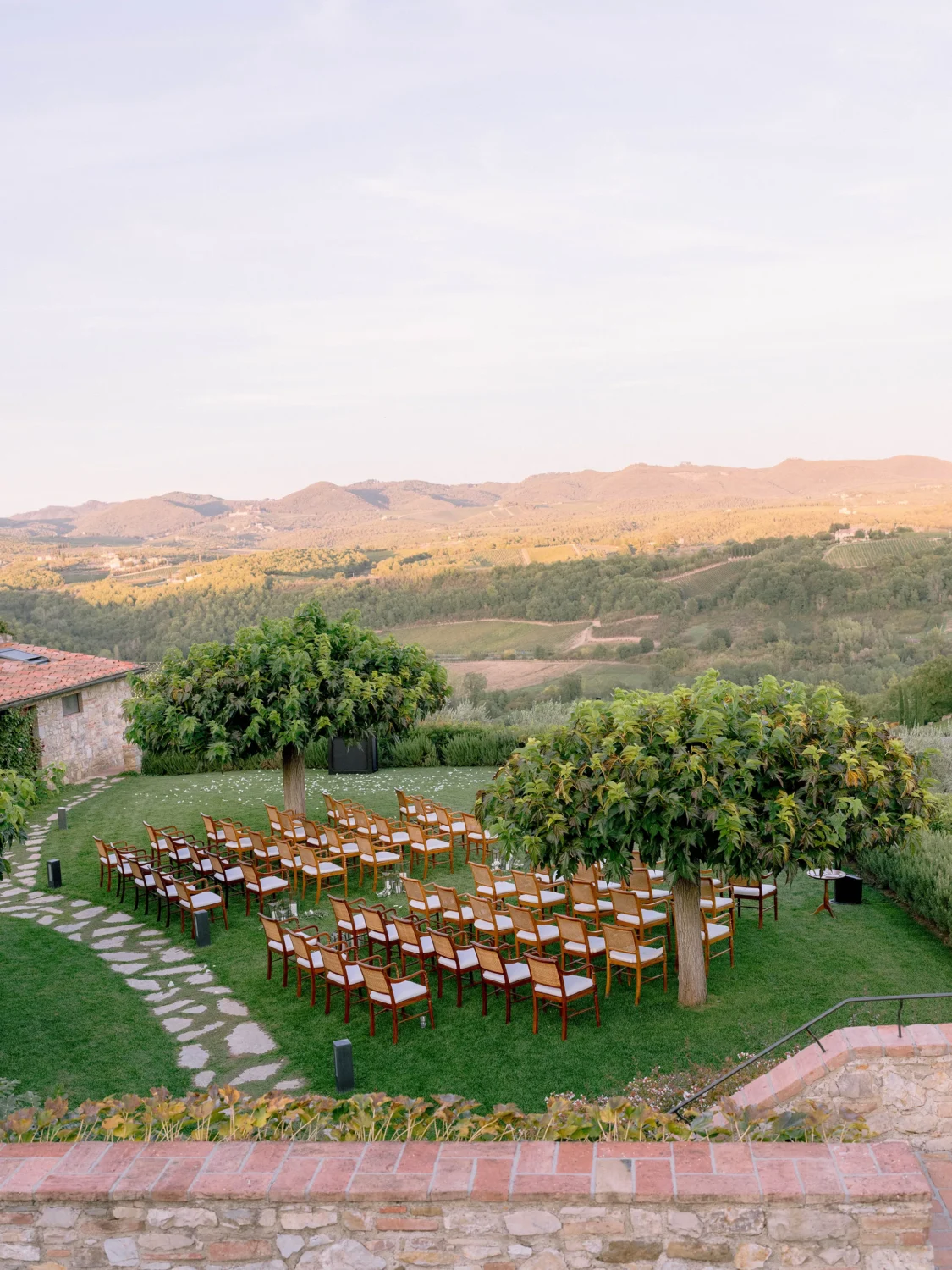 Outdoor wedding ceremony setup with chairs arranged on a grassy lawn overlooking rolling hills.