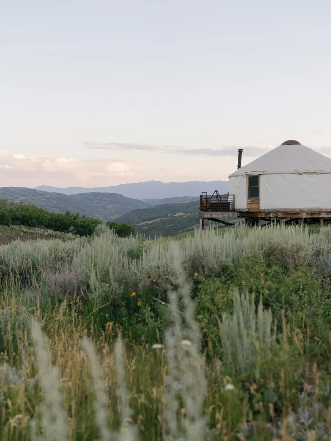 Luxury yurt on a hilltop overlooking a mountain range.