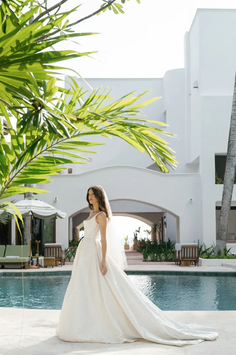 Bride in elegant wedding gown by the pool, styled shoot.