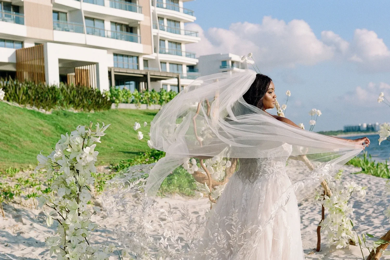 Bride in a flowing wedding dress and veil on a beach, styled shoot.
