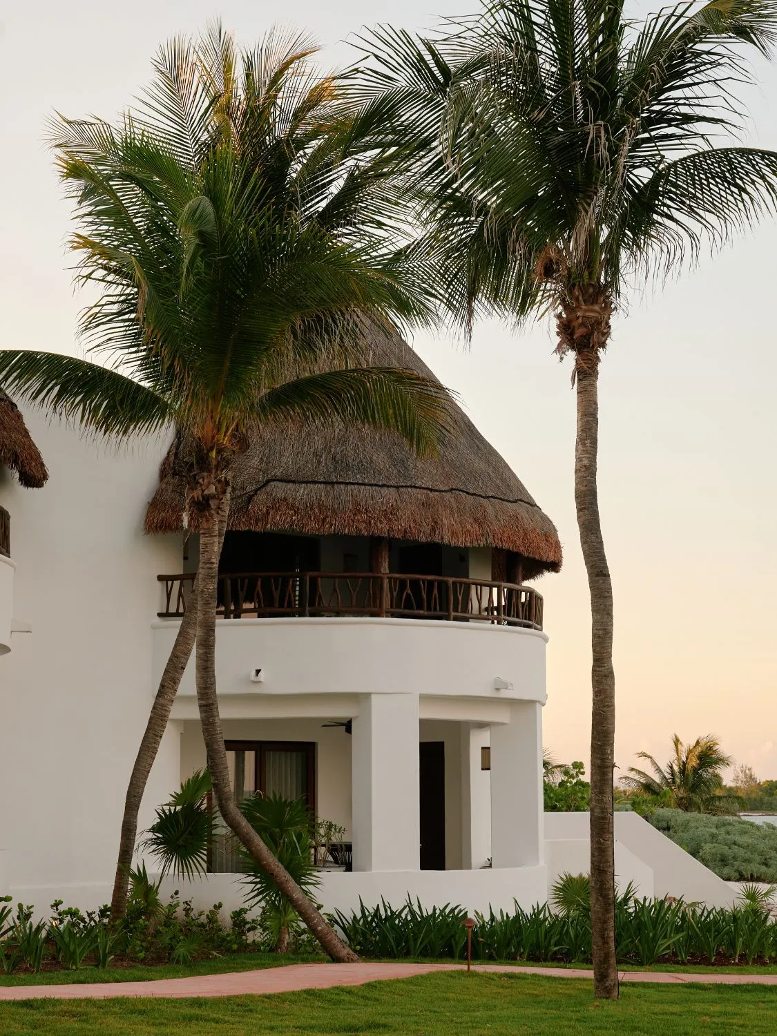 Luxury resort suite with thatched roof and palm trees.