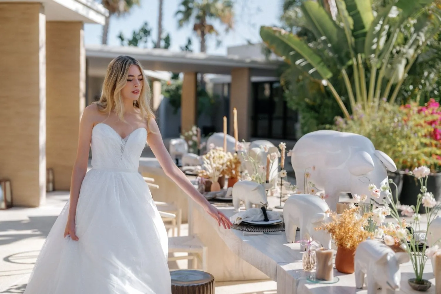 Bride in a strapless wedding gown at a styled shoot with pig figurines on a table.