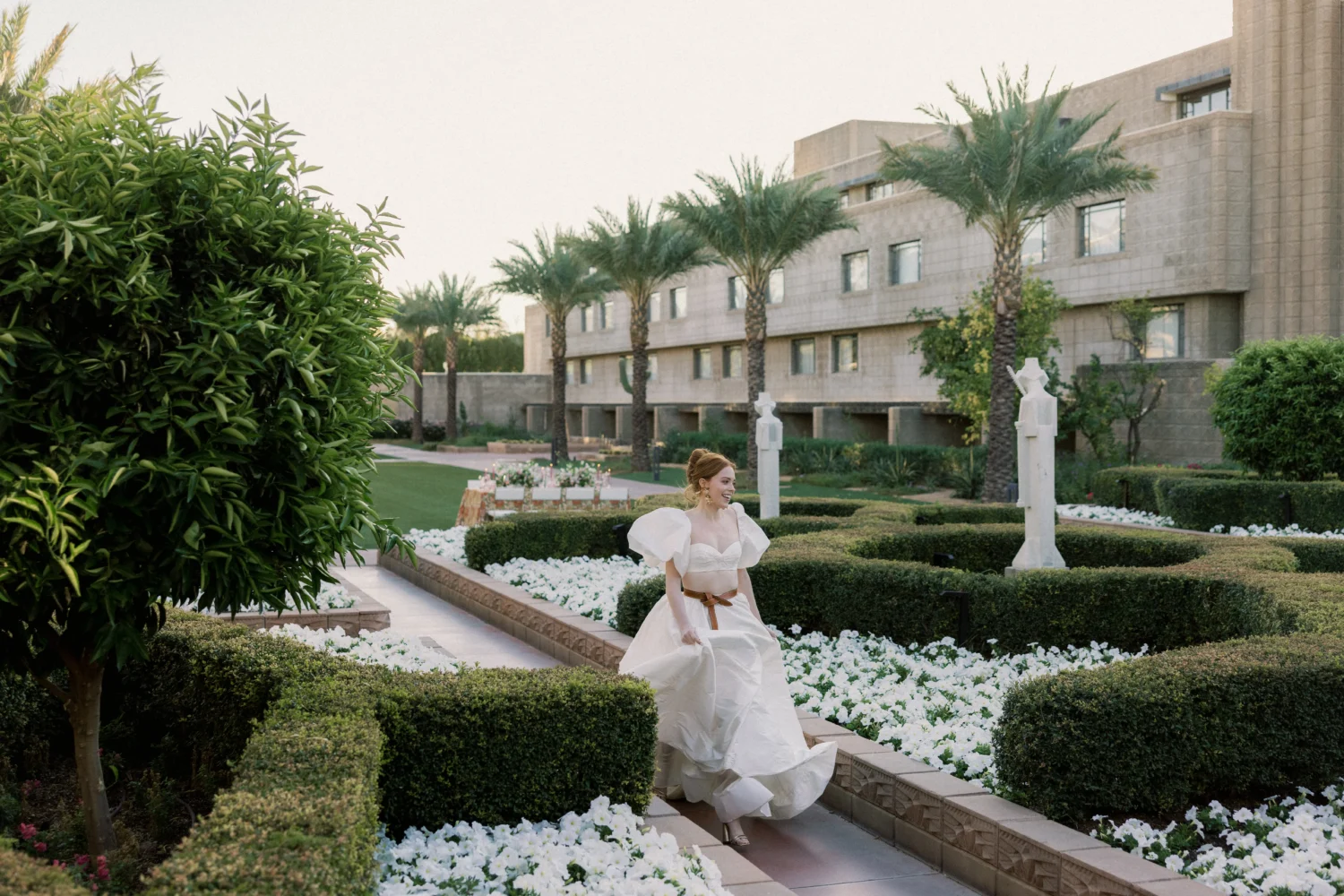 Bride in a stylish off-white gown walks through a garden during a styled shoot.