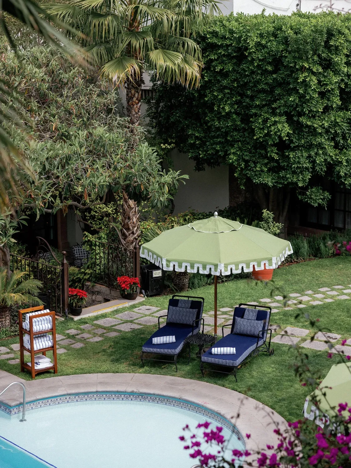 Luxury resort poolside: two lounge chairs under a green umbrella, inviting relaxation.