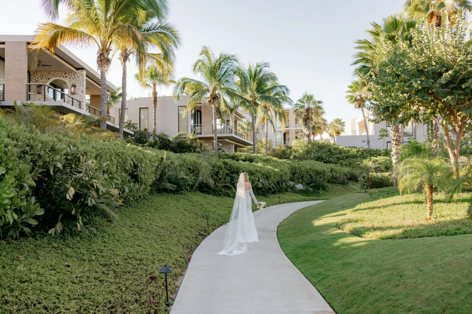 Bride in wedding dress walking down a path toward luxury villas, styled shoot