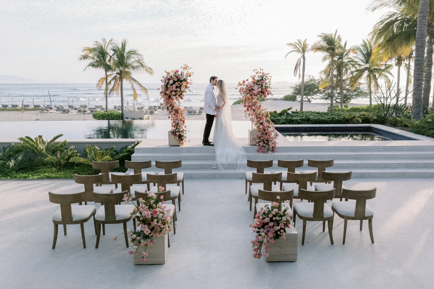 Beach wedding ceremony setup with floral arch and couple. Styled shoot.