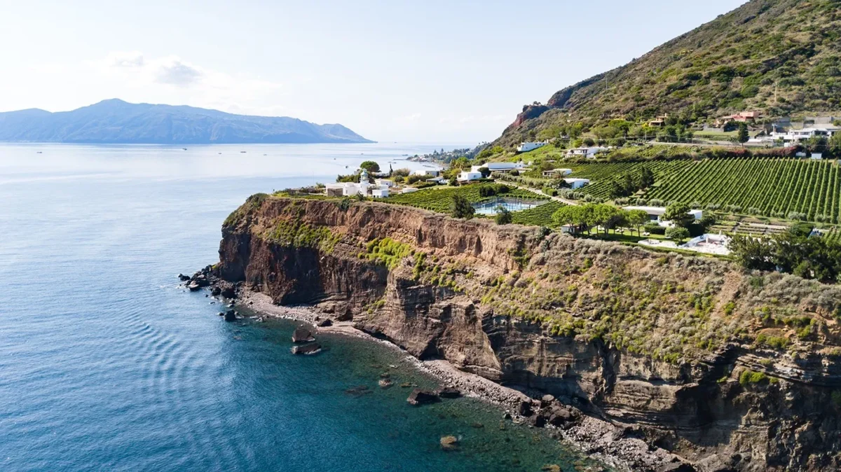 Aerial view of a private island with vineyards, luxury villas, and a lighthouse, perfect for private island weddings.