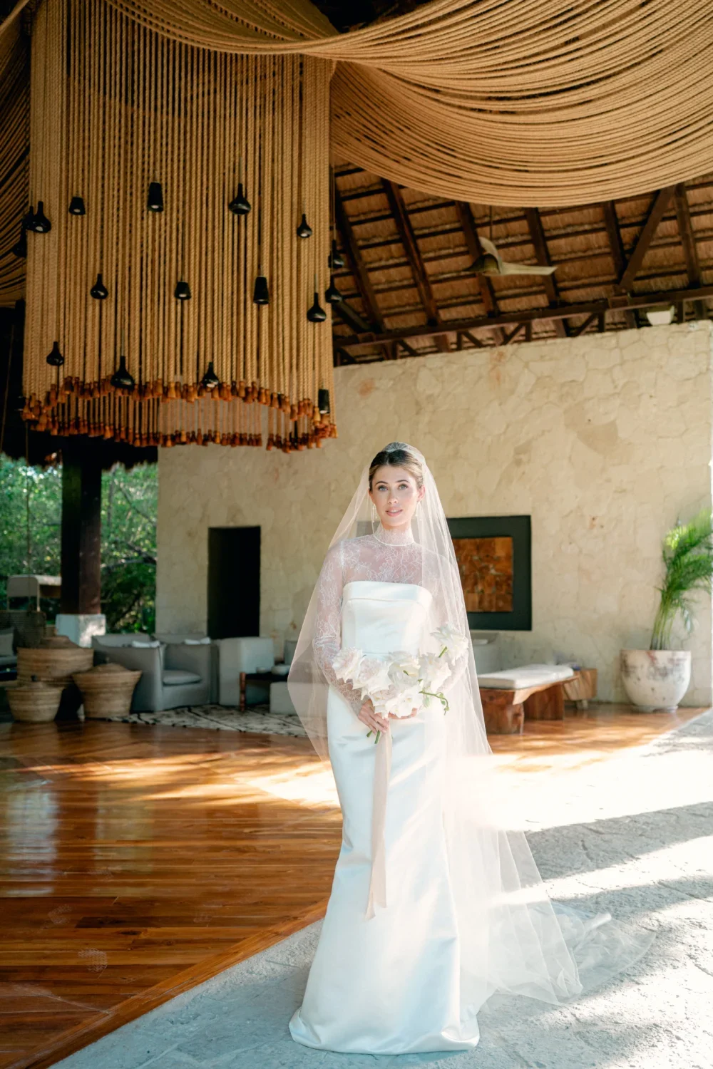 Bride in elegant wedding gown, holding bouquet, styled shoot.