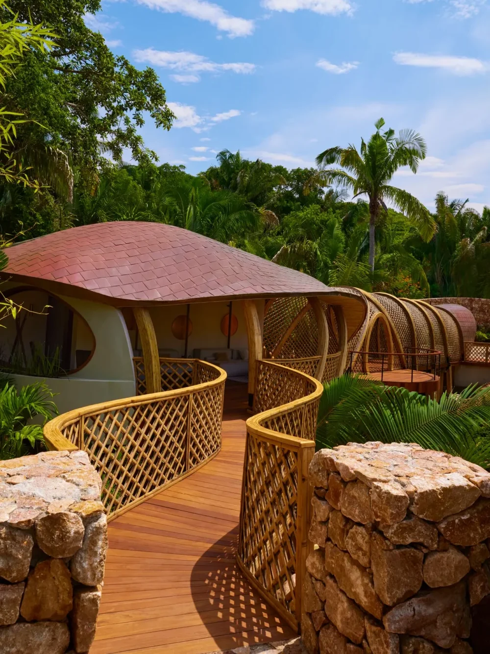 Luxury eco-friendly resort with bamboo walkway and dome-shaped villas.