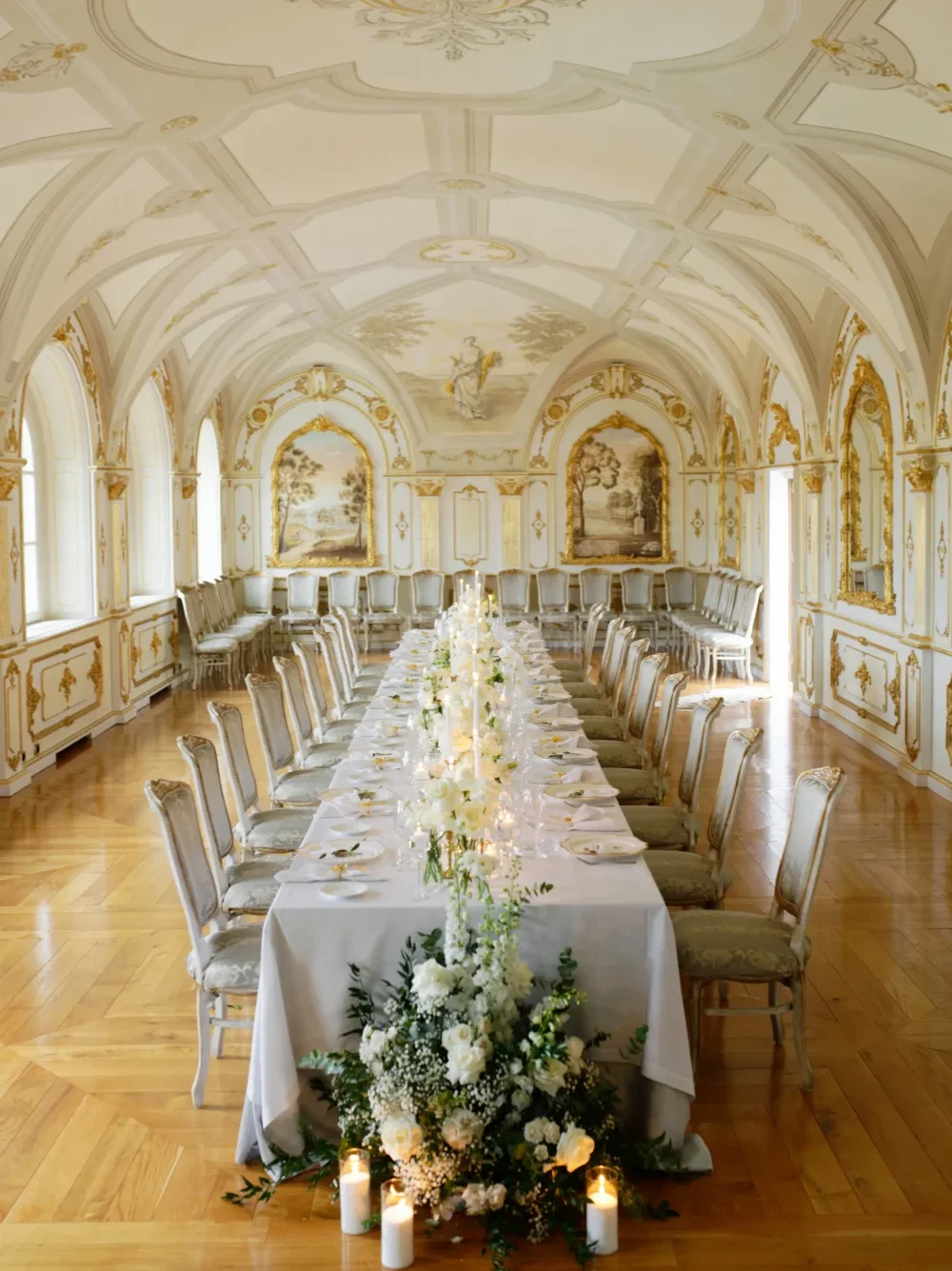 Elegant long wedding table with white flowers and candles in a grand ballroom. A perfect partnership for a memorable event.