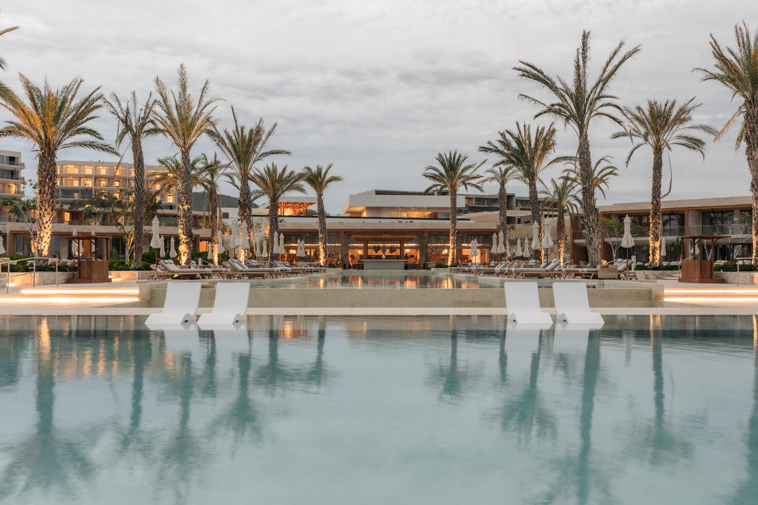 Park Hyatt Los Cabos wedding venue: luxurious pool with palm trees and modern architecture at sunset.