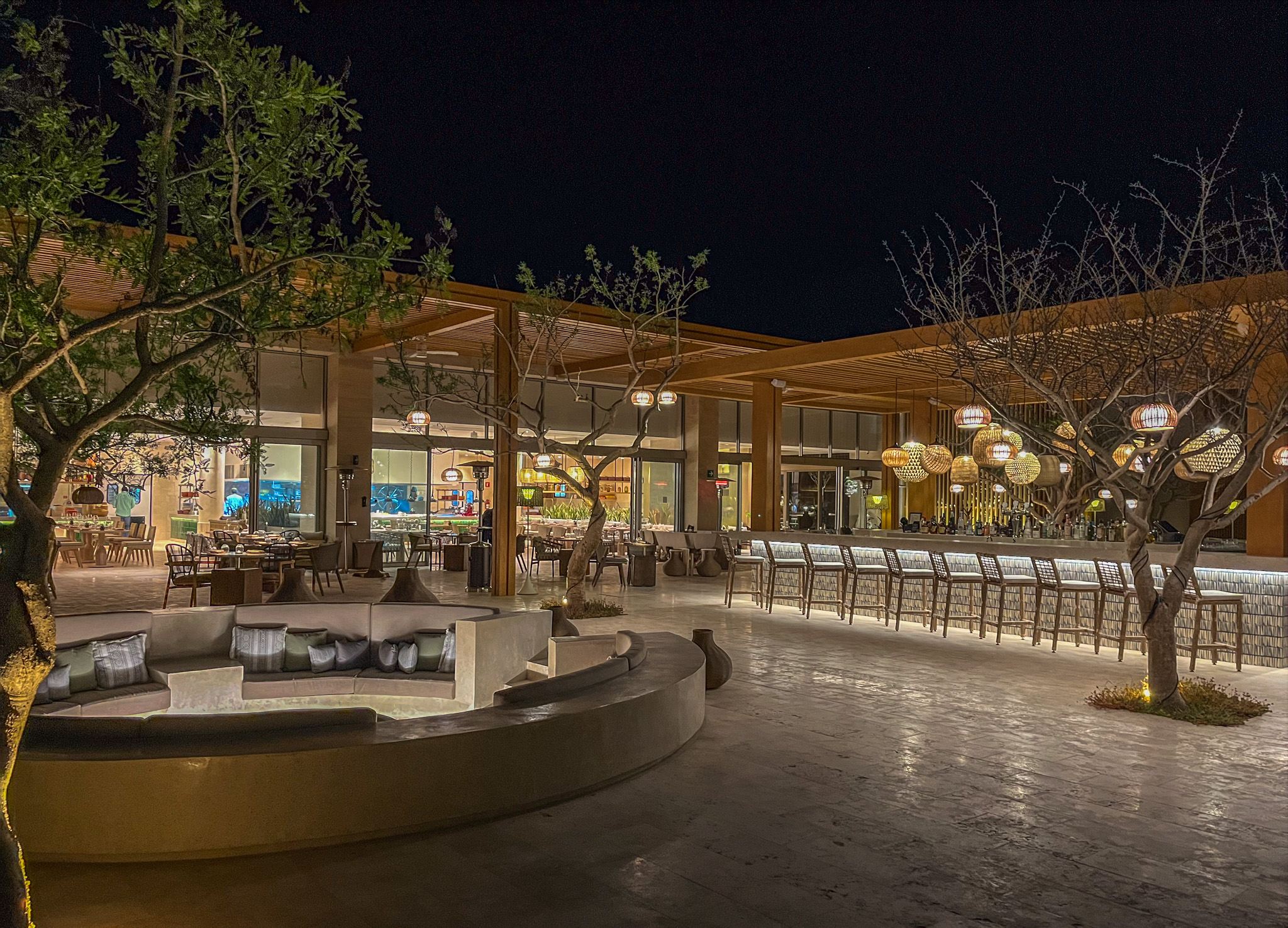 Park Hyatt Cabo del Sol outdoor bar area at night with trees and decorative lighting.