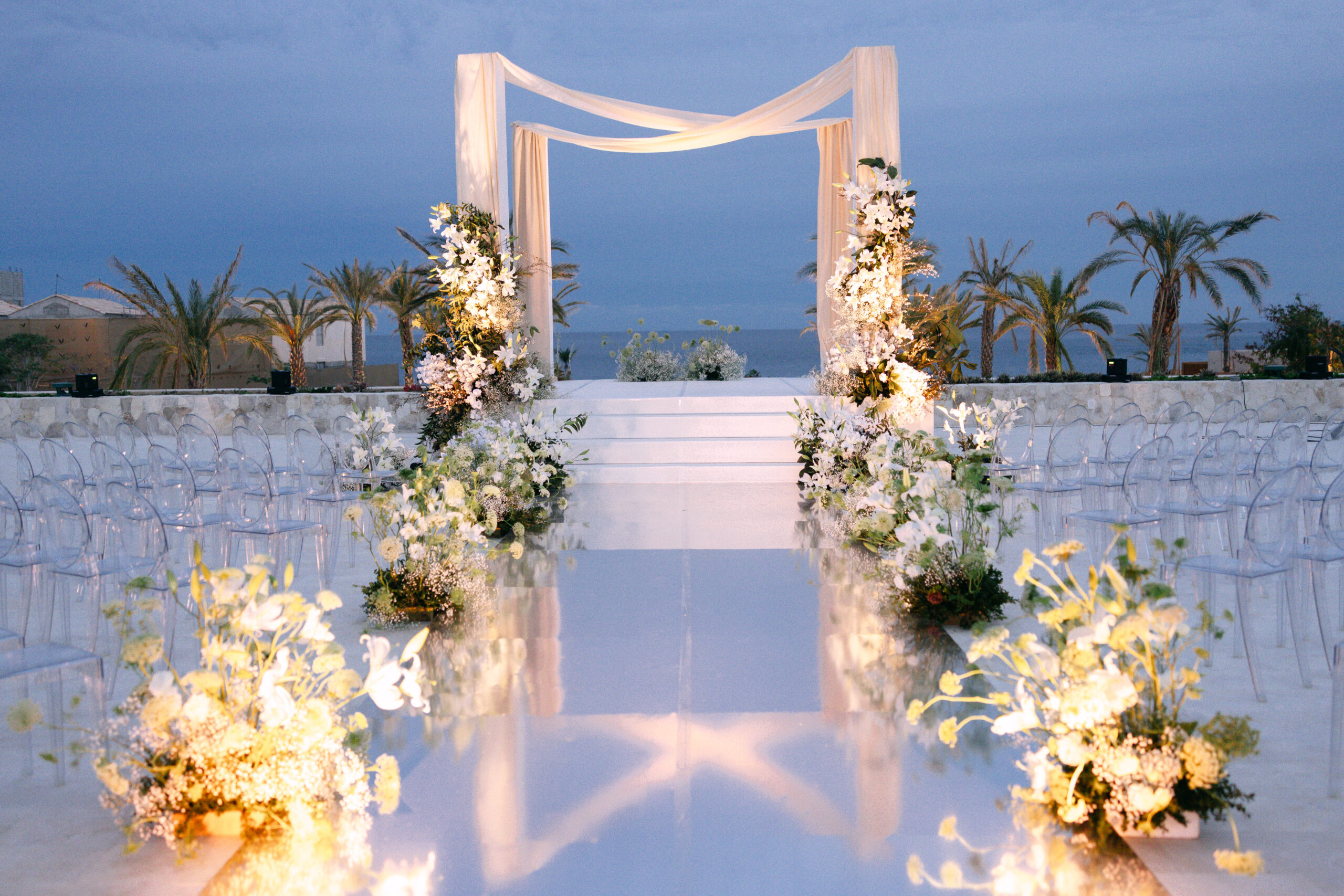 Park Hyatt Los Cabos wedding ceremony with white floral arrangements and clear chairs.