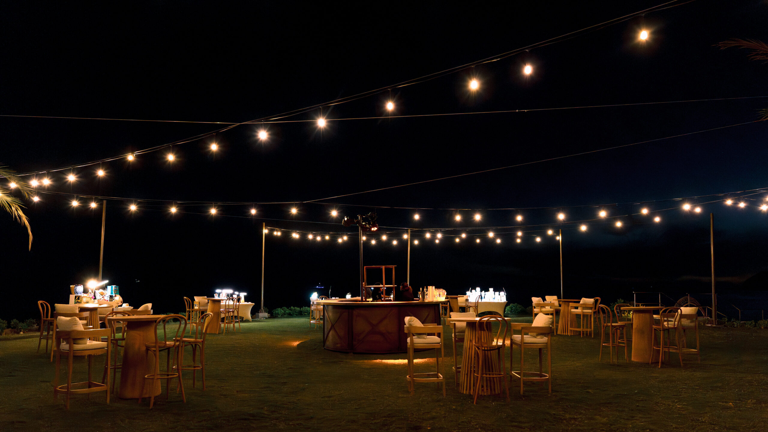 Park Hyatt Los Cabos wedding reception at night, with string lights and cocktail tables on the lawn.