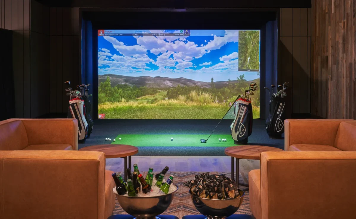 Golf simulator at Montage Big Sky: Luxurious setup with golf clubs, screen displaying a golf course, and refreshments.