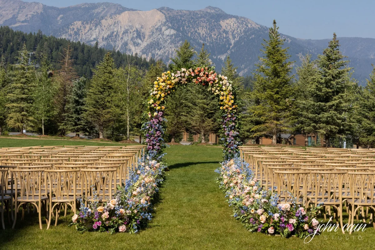 Wedding ceremony at Montage Big Sky, a Montana wedding venue, with floral arch and mountain backdrop.