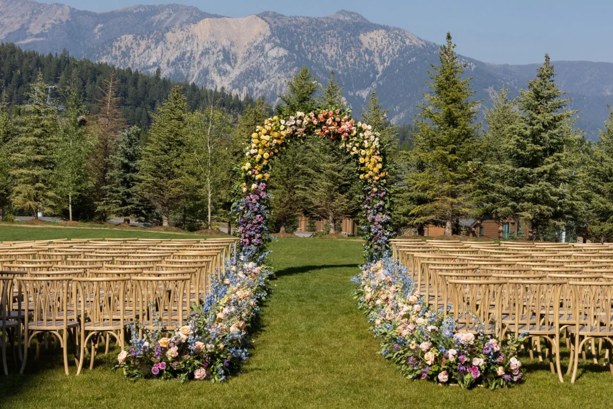 Wedding ceremony at Montage Big Sky, Montana wedding venue, with floral arch and mountain backdrop.