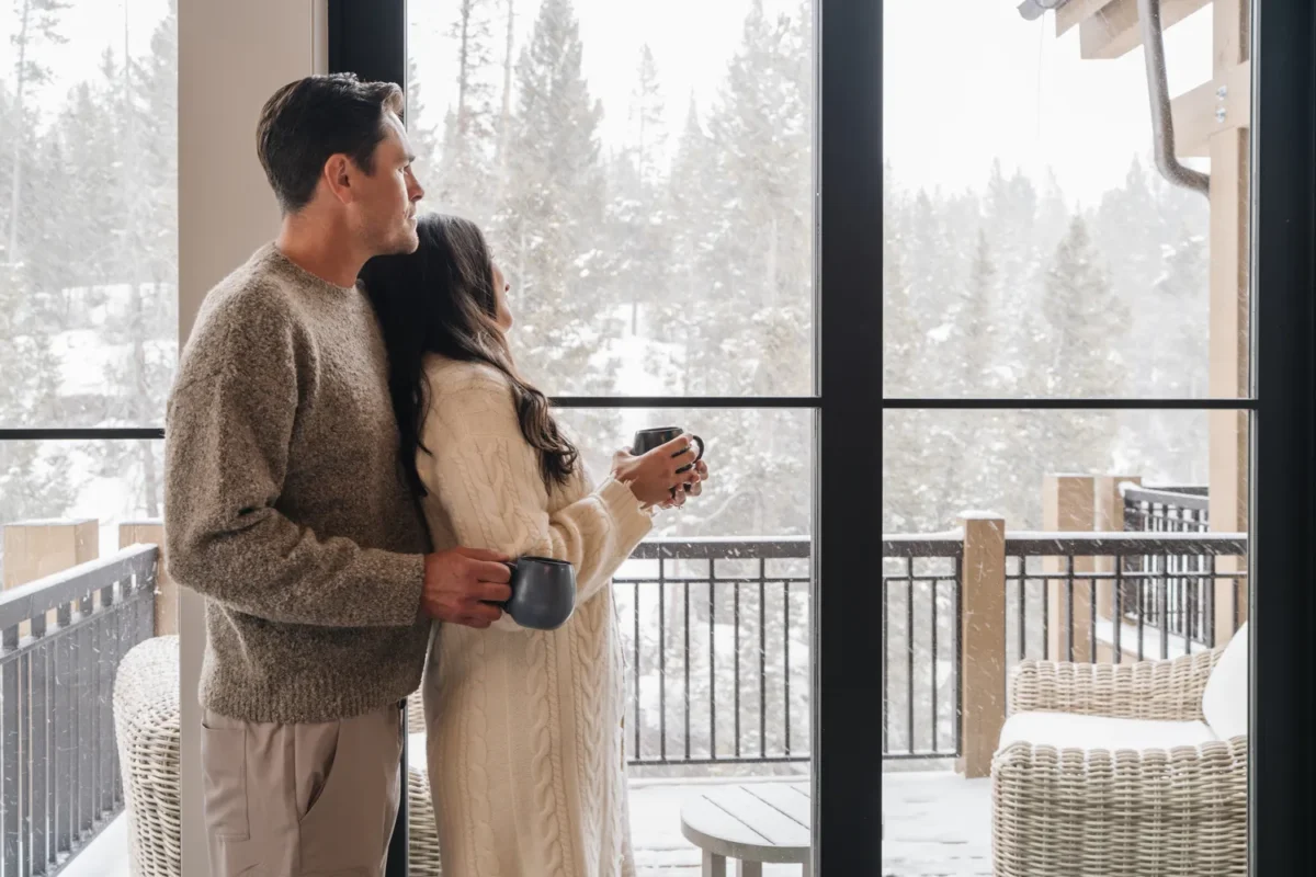 Couple gazing at snowy landscape from a Montage Big Sky cabin window