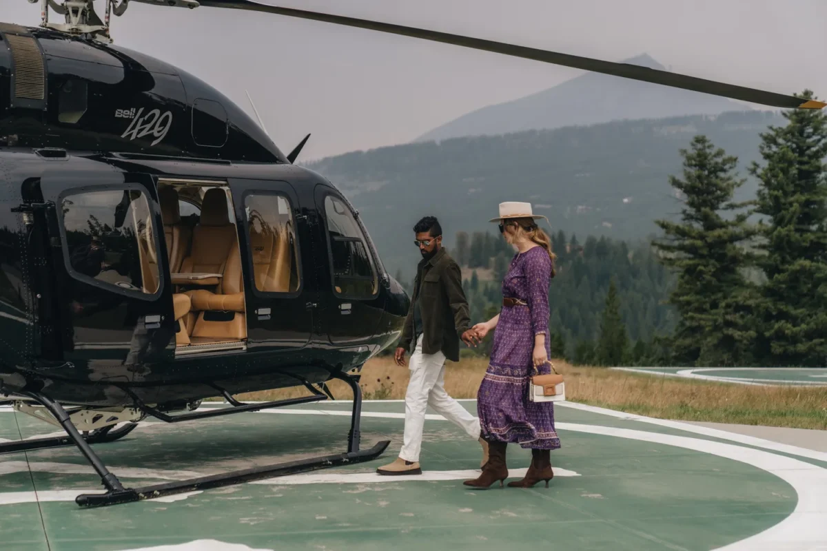 Couple holding hands walking near a helicopter at a Montana wedding venue.